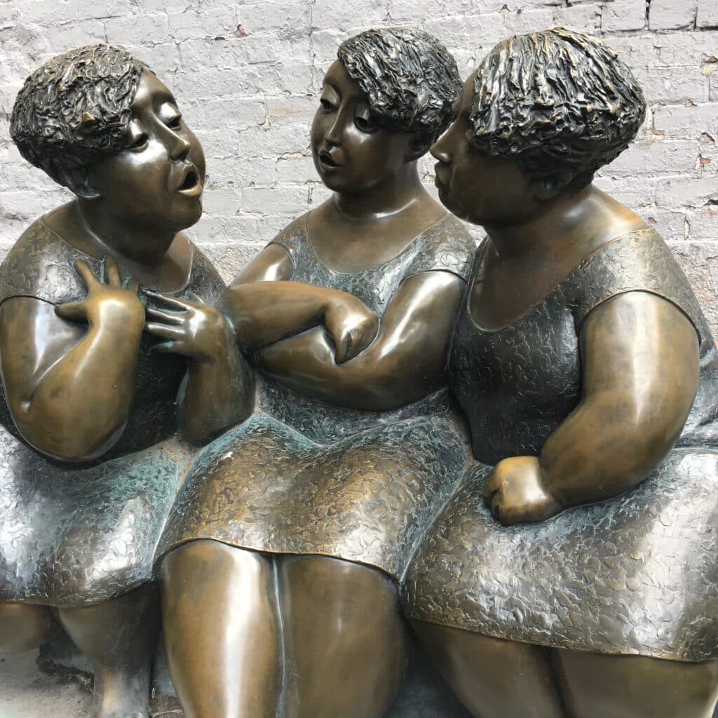 Bronze sculpture of three seated women in conversation