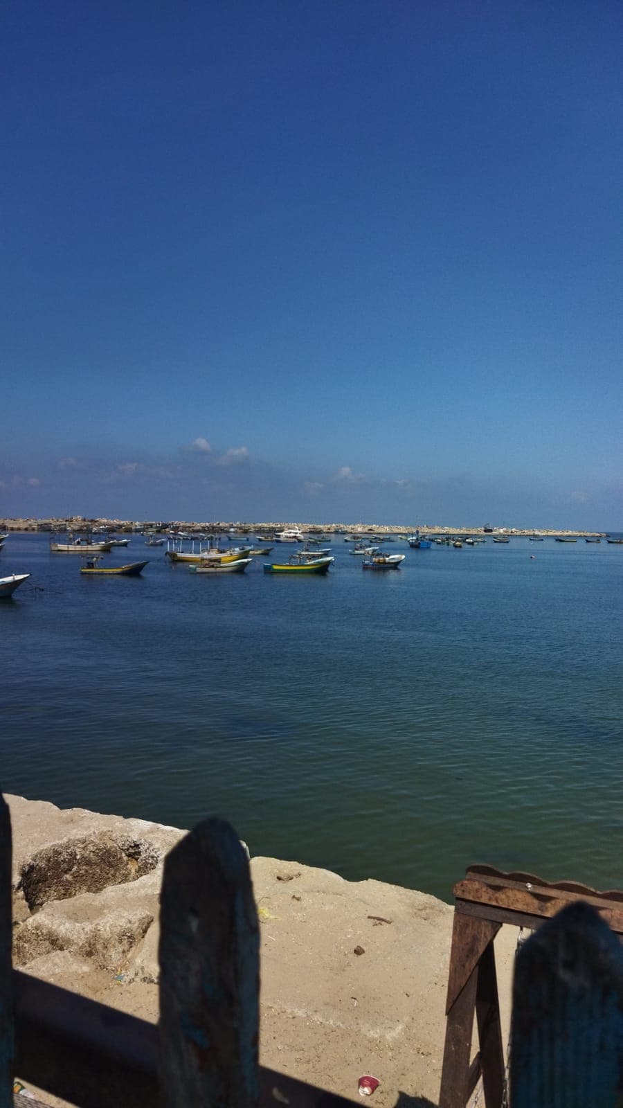 Fishing boats moored in a harbor beneath a wide blue sky